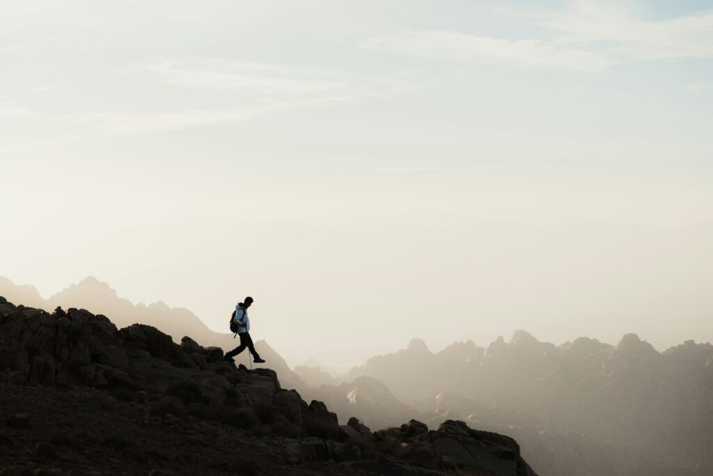 a man running up a mountain with a sky background