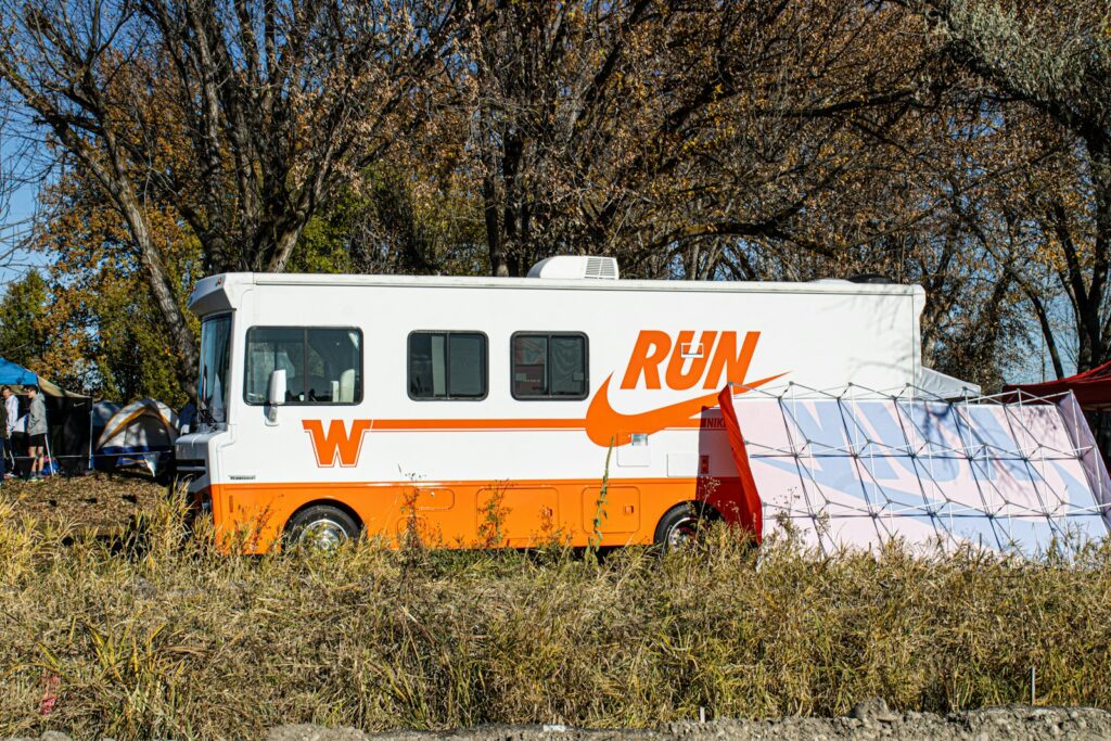 An orange and white food truck parked in a field