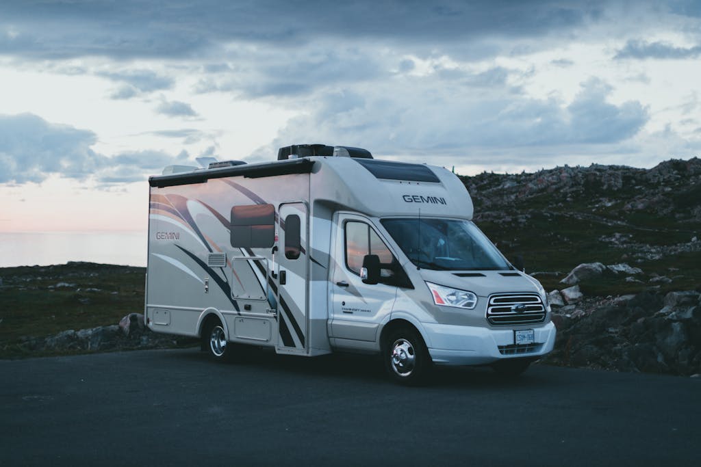 A sleek RV parked at dusk in a scenic natural landscape with rocky terrain.